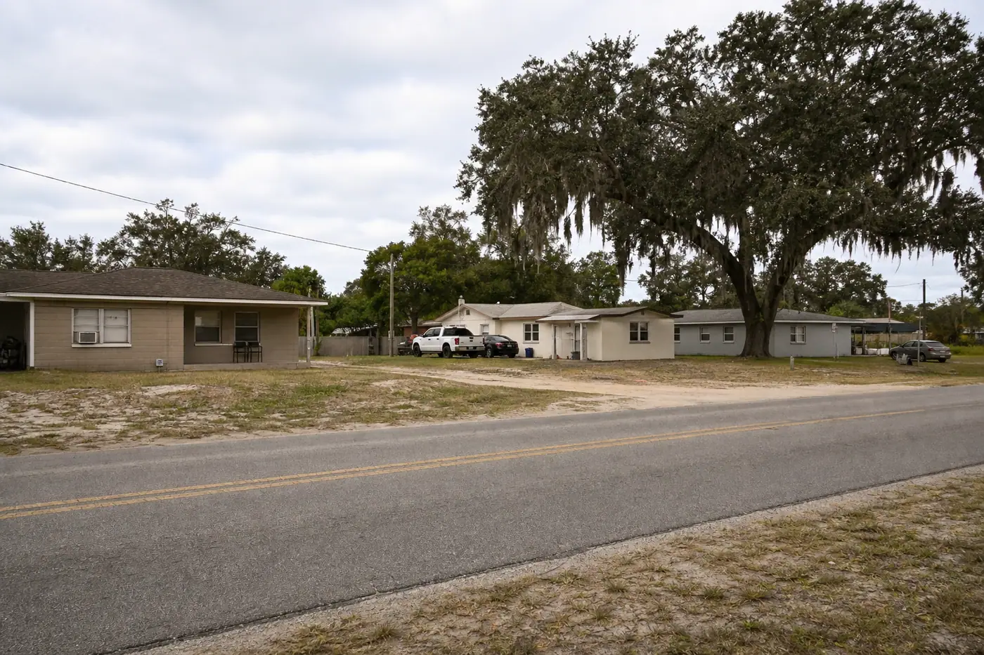 A quiet residential street of concrete-block homes under live oaks in Mulberry, Florida.