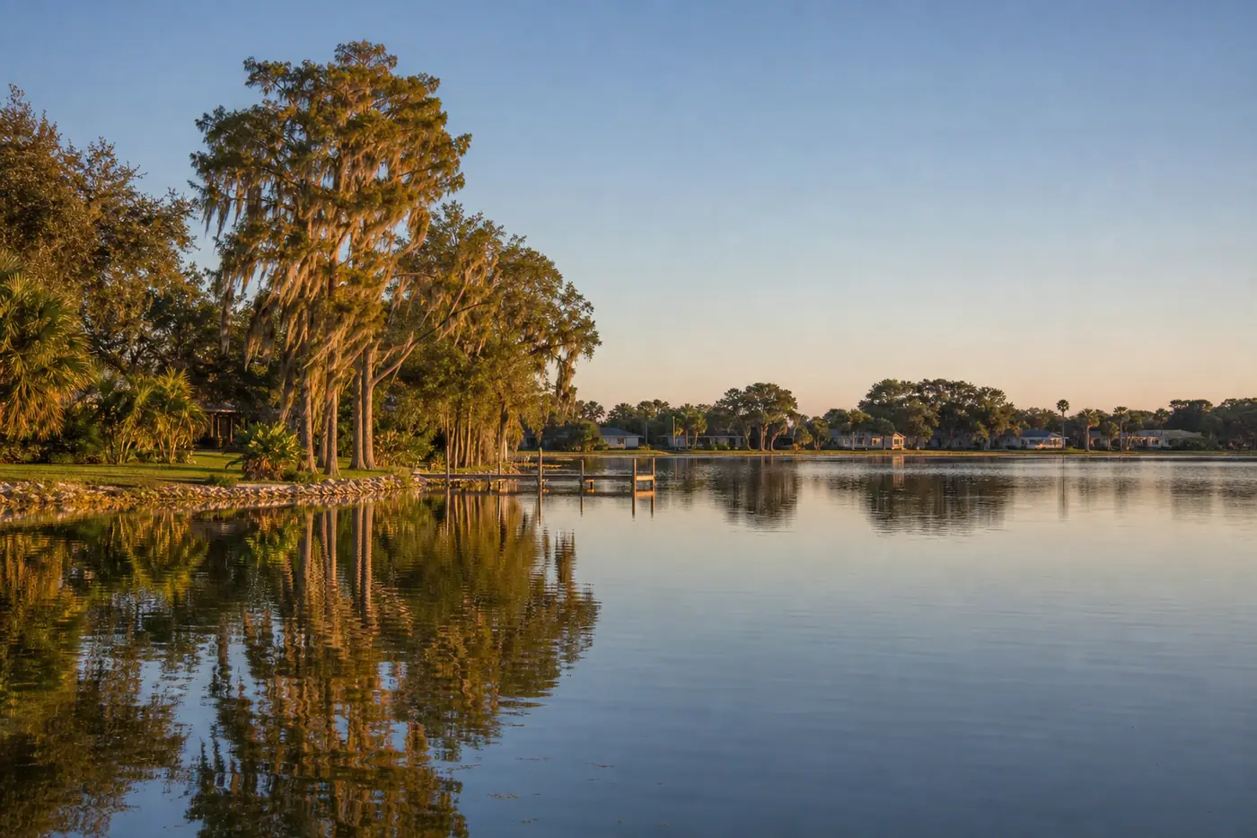 Winter Haven Chain of Lakes shoreline with cypress trees, a wooden dock, and lakefront homes.